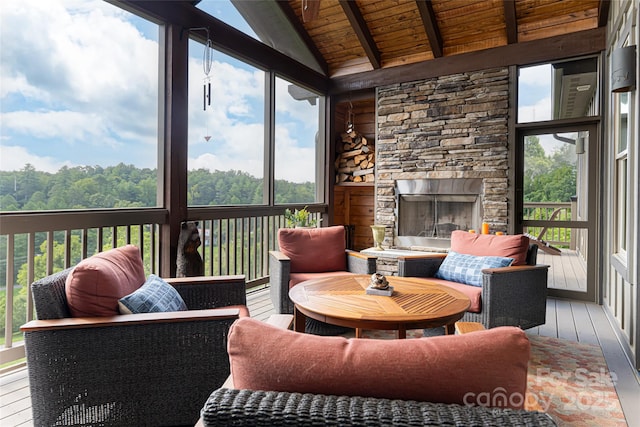 sunroom featuring vaulted ceiling with beams, a stone fireplace, and wooden ceiling