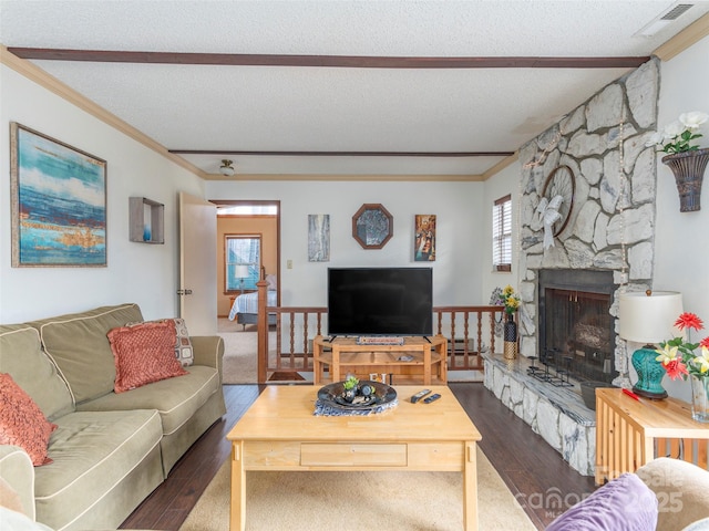 living room with dark wood-type flooring, a textured ceiling, and a stone fireplace