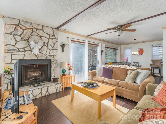 living room with hardwood / wood-style floors, a stone fireplace, ornamental molding, a textured ceiling, and ceiling fan with notable chandelier