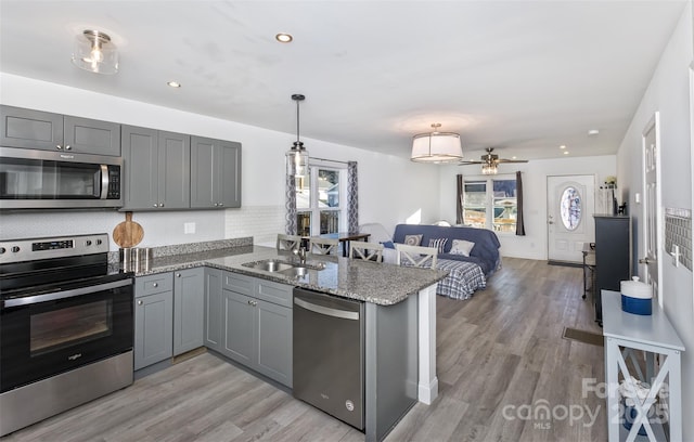 kitchen with kitchen peninsula, gray cabinets, decorative light fixtures, and appliances with stainless steel finishes