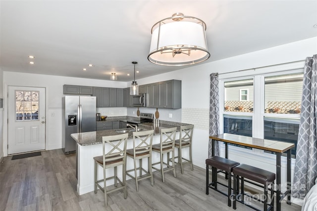 kitchen with decorative light fixtures, kitchen peninsula, gray cabinets, and stainless steel appliances