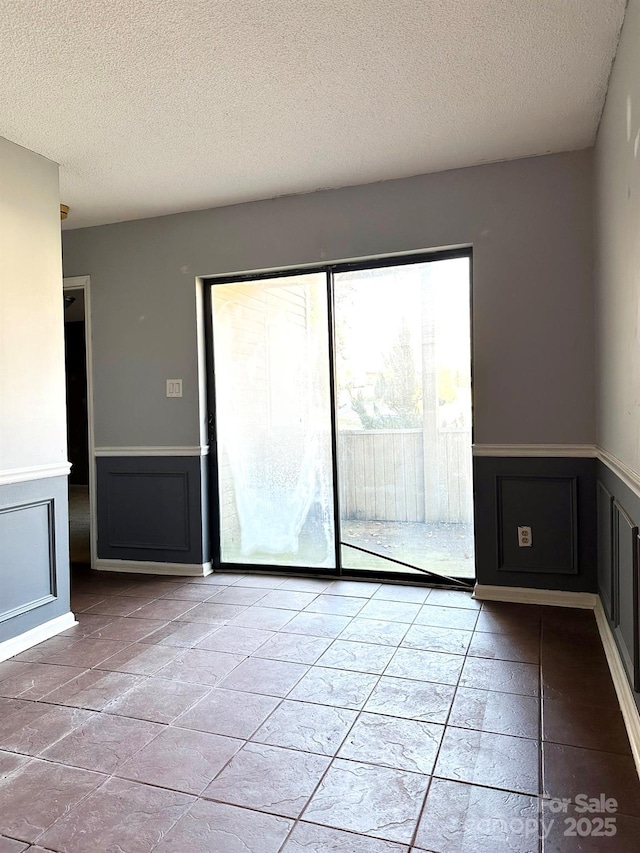 empty room with a textured ceiling and light tile patterned floors