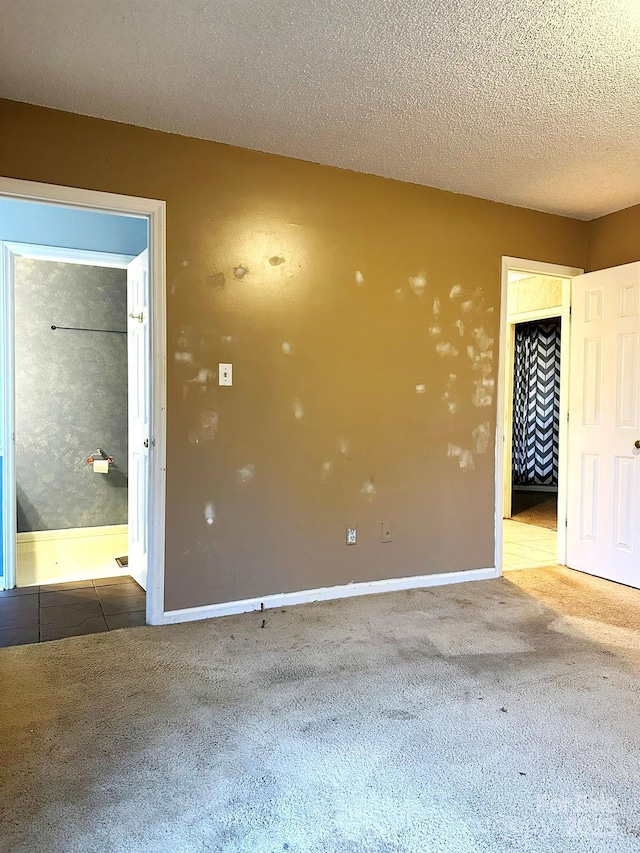 unfurnished room featuring a textured ceiling and dark carpet