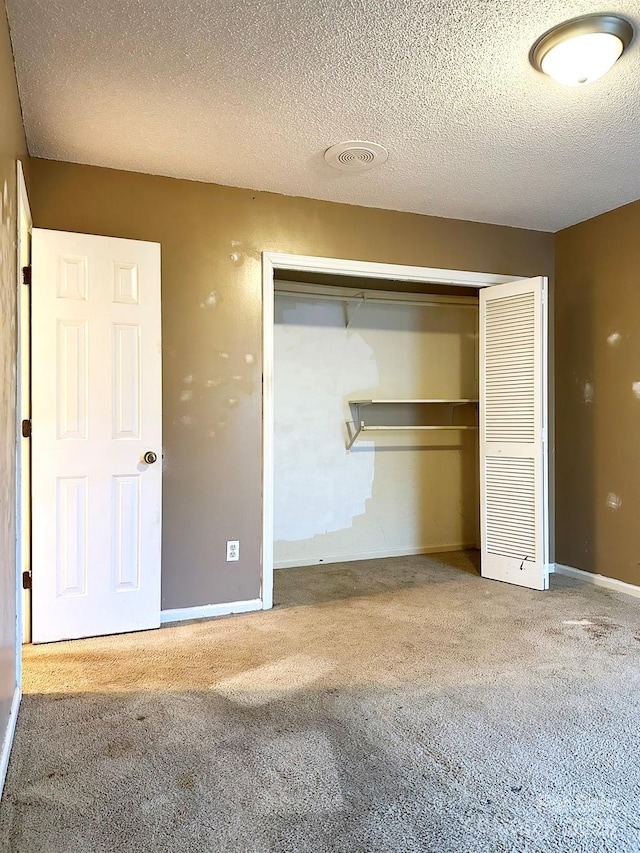 unfurnished bedroom with a closet, a textured ceiling, and carpet floors