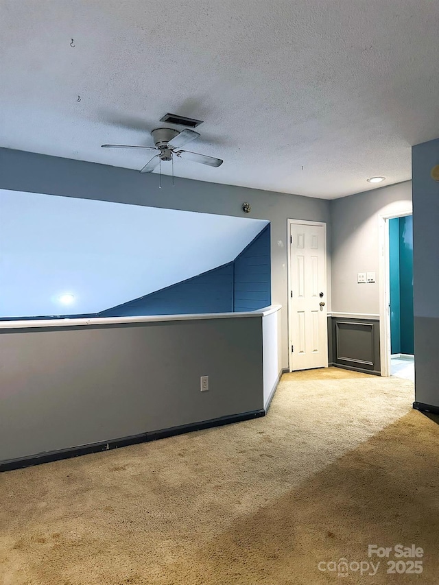 carpeted spare room with a textured ceiling and ceiling fan