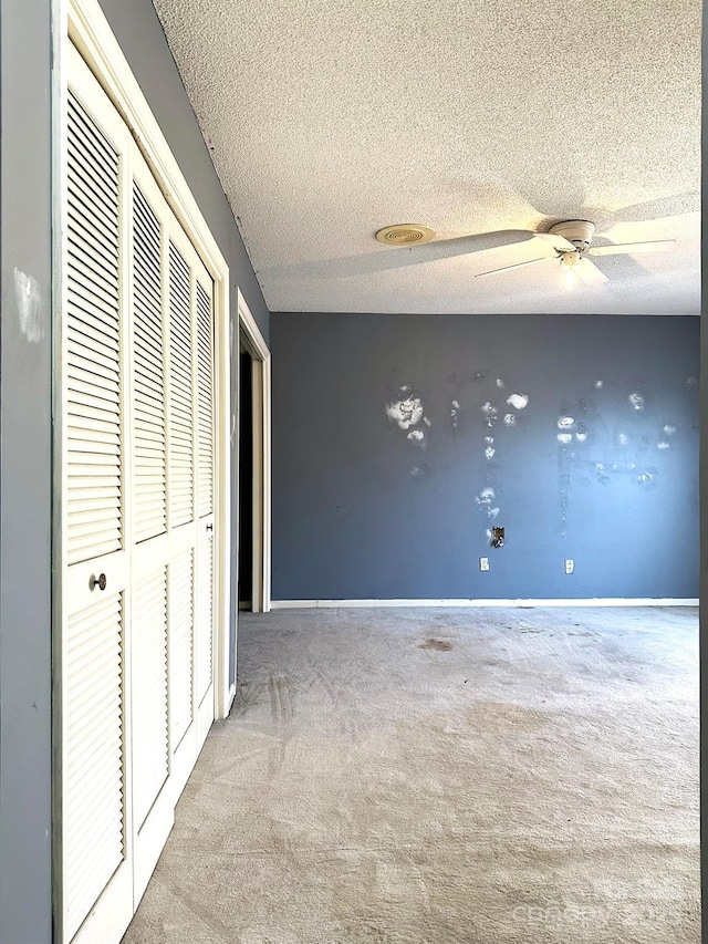 unfurnished bedroom featuring a closet, a textured ceiling, ceiling fan, and light colored carpet