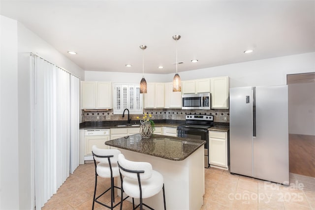 kitchen with pendant lighting, sink, light tile patterned floors, appliances with stainless steel finishes, and a kitchen island