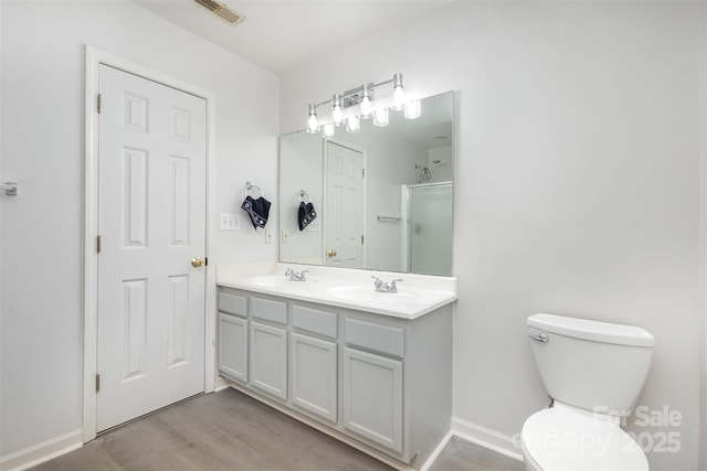 bathroom with an enclosed shower, vanity, hardwood / wood-style floors, and toilet