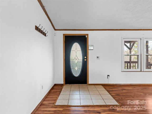 entrance foyer with a textured ceiling, ornamental molding, and hardwood / wood-style flooring