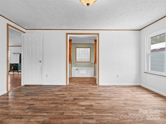 unfurnished bedroom featuring a textured ceiling, crown molding, wood-type flooring, and multiple windows