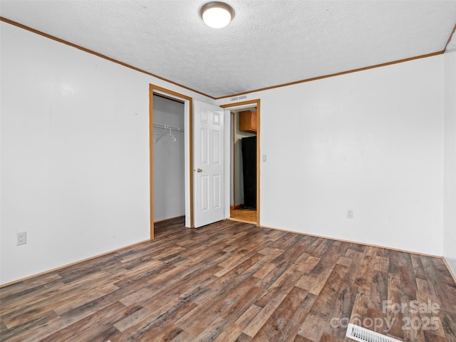 spare room with a textured ceiling, dark wood-type flooring, and ornamental molding