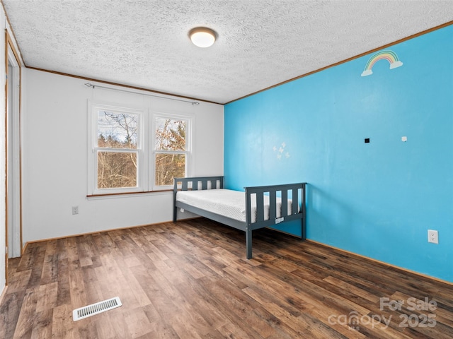 unfurnished bedroom featuring a textured ceiling, dark hardwood / wood-style floors, and crown molding