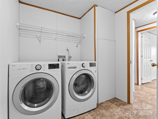 clothes washing area with washer and clothes dryer, ornamental molding, and a textured ceiling