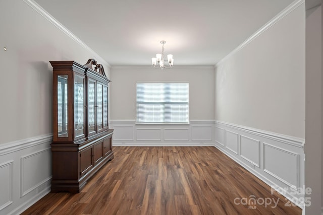 unfurnished dining area with an inviting chandelier, ornamental molding, and dark wood-type flooring