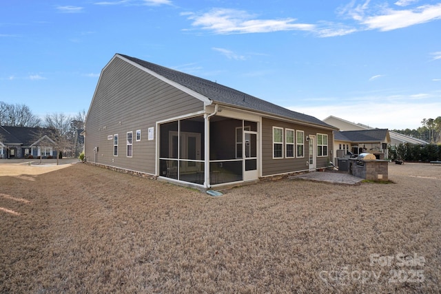 rear view of property featuring an outdoor kitchen and a sunroom