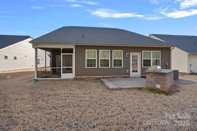 rear view of house with exterior kitchen, a patio area, and a sunroom