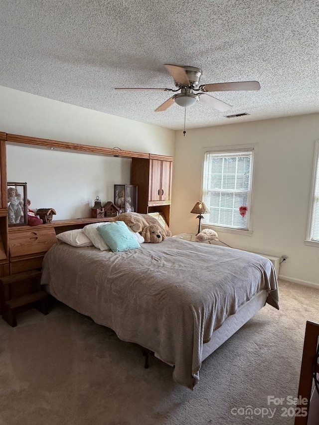 bedroom with ceiling fan, carpet, and a textured ceiling