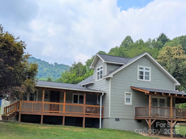 rear view of house with a wooden deck and a lawn