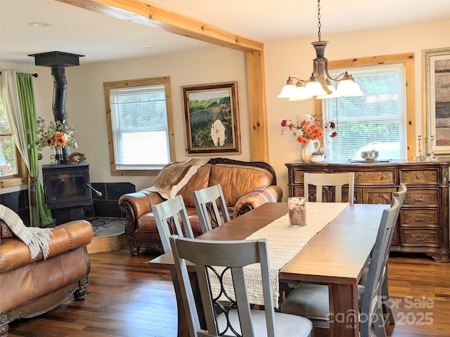 dining space with a notable chandelier, dark hardwood / wood-style floors, and a wood stove