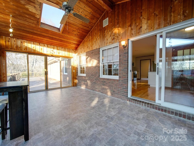 unfurnished sunroom featuring ceiling fan, wooden ceiling, and lofted ceiling with skylight