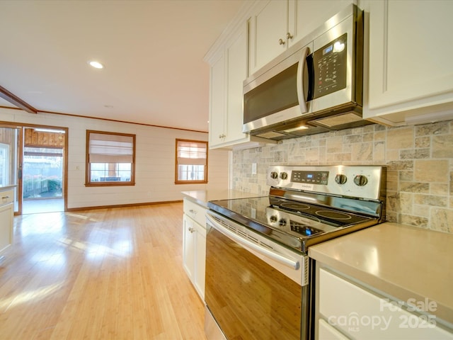 kitchen with white cabinetry, light hardwood / wood-style floors, stainless steel appliances, tasteful backsplash, and crown molding