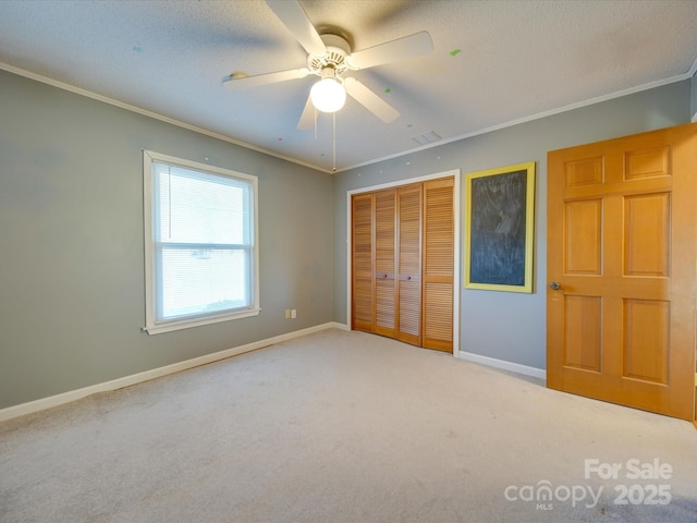 unfurnished bedroom featuring ceiling fan, carpet flooring, a closet, and crown molding