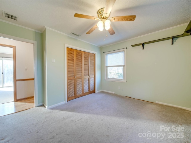 unfurnished bedroom featuring ceiling fan, light colored carpet, multiple windows, and a closet