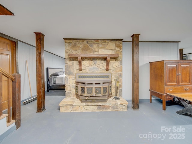 living room with wood walls, a wood stove, and concrete flooring