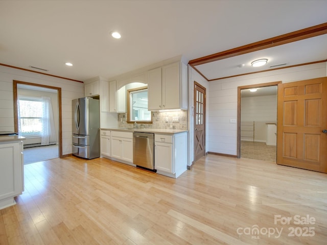 kitchen with white cabinetry, appliances with stainless steel finishes, crown molding, light hardwood / wood-style flooring, and sink