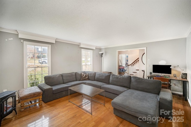 living room with a wood stove, hardwood / wood-style flooring, crown molding, and a textured ceiling