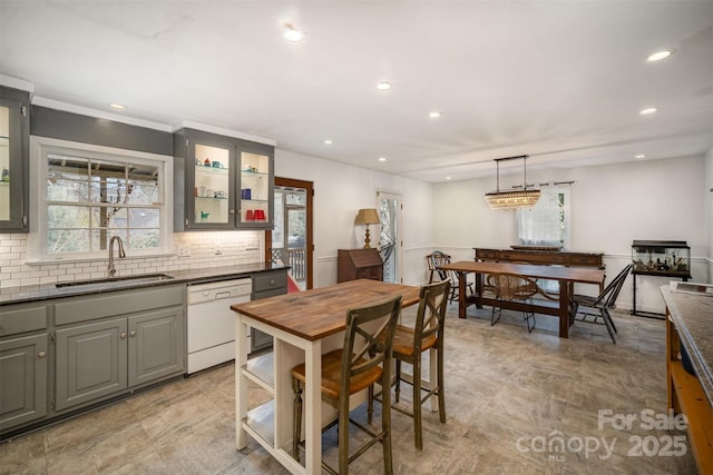 kitchen with gray cabinetry, hanging light fixtures, sink, backsplash, and dishwasher