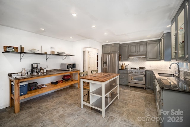 kitchen with sink, gray cabinets, tasteful backsplash, dark stone counters, and appliances with stainless steel finishes