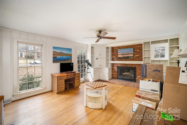 living room with a brick fireplace, plenty of natural light, built in features, and hardwood / wood-style flooring