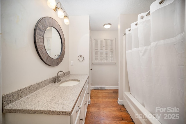 bathroom featuring hardwood / wood-style flooring, vanity, and a textured ceiling