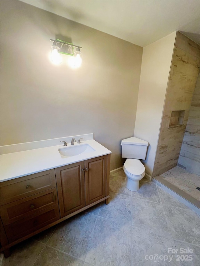 bathroom with toilet, vanity, and tiled shower