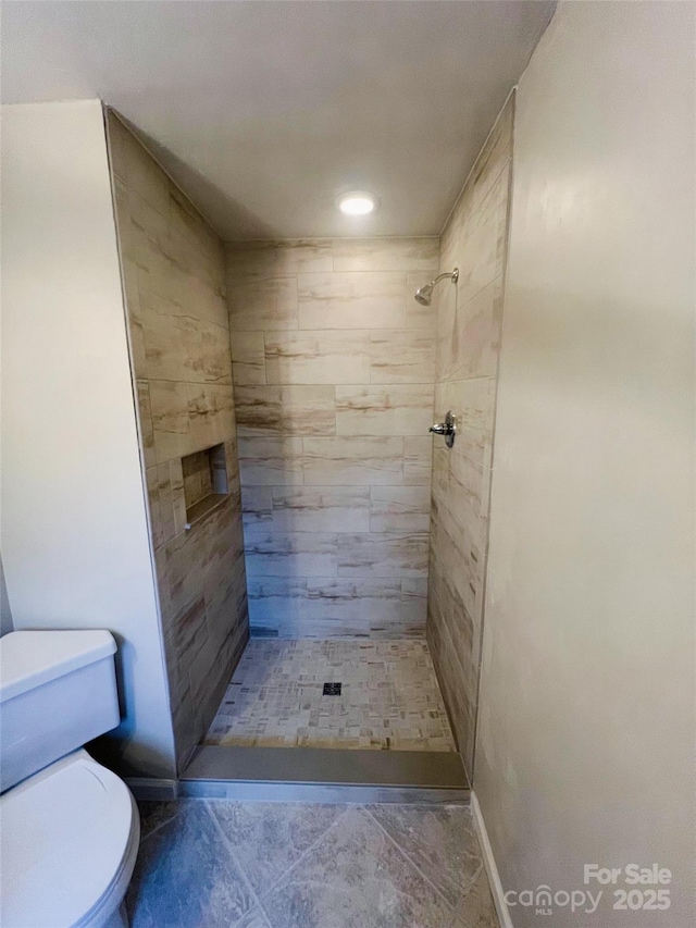 bathroom featuring a tile shower and toilet