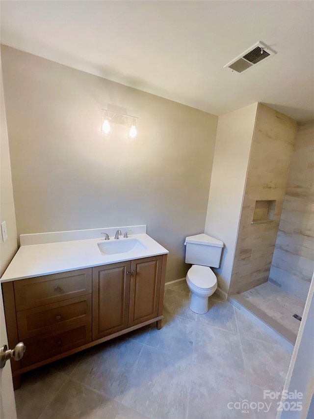 bathroom with vanity, tiled shower, toilet, and tile patterned floors