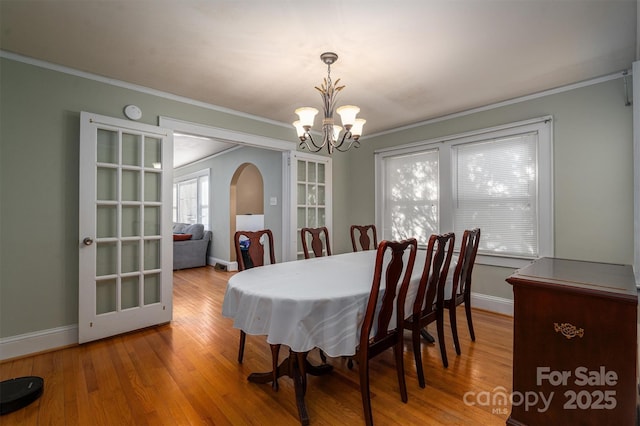 dining area with crown molding, hardwood / wood-style floors, and an inviting chandelier