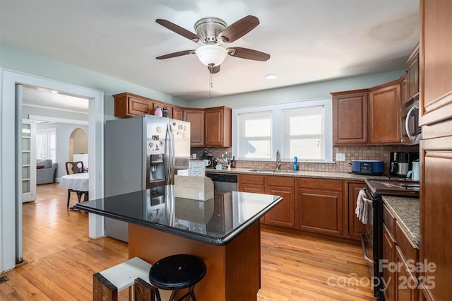 kitchen featuring sink, a center island, dark stone counters, and stainless steel appliances