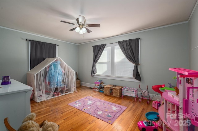 recreation room with ceiling fan, crown molding, and wood-type flooring