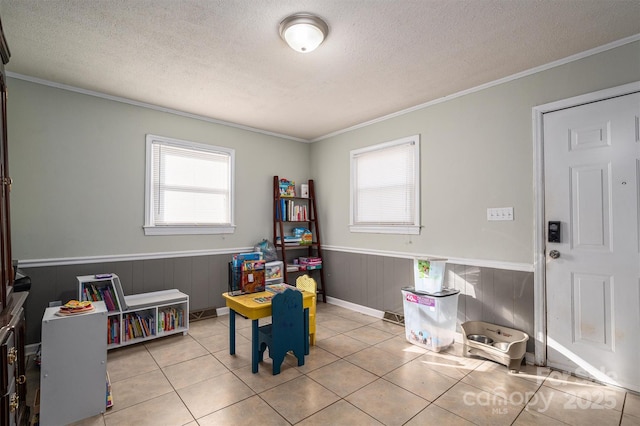 recreation room featuring a textured ceiling, light tile patterned floors, and ornamental molding