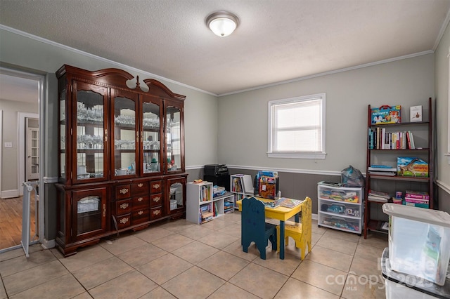 playroom with a textured ceiling, light tile patterned floors, and ornamental molding