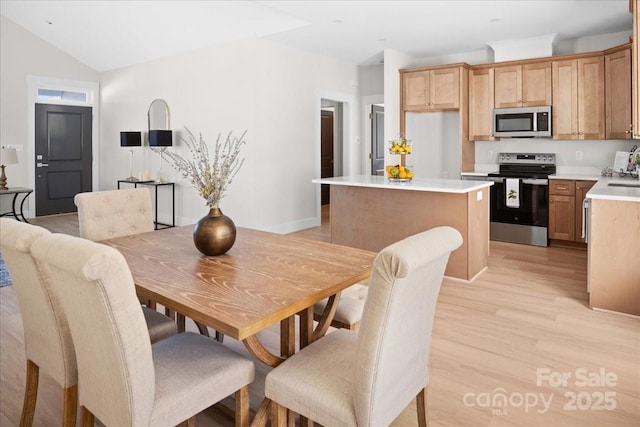 dining room featuring light hardwood / wood-style floors and vaulted ceiling