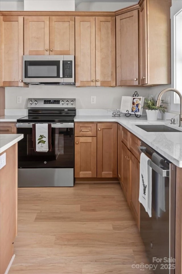 kitchen featuring stainless steel appliances, light wood-type flooring, and sink