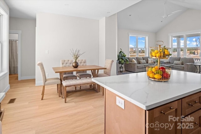 kitchen featuring ceiling fan, light hardwood / wood-style flooring, a center island, and light stone counters