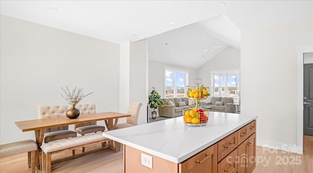 kitchen with a kitchen island, vaulted ceiling, ceiling fan, and light hardwood / wood-style flooring