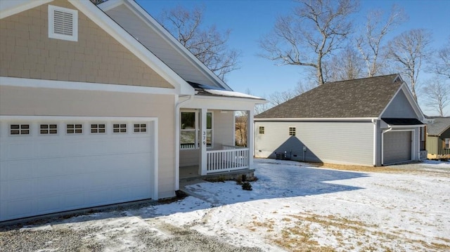 view of snowy exterior featuring covered porch and a garage