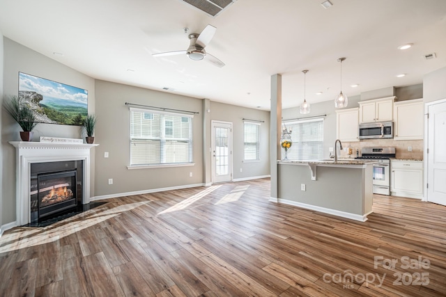 kitchen featuring pendant lighting, a breakfast bar, light wood-type flooring, stainless steel appliances, and white cabinets