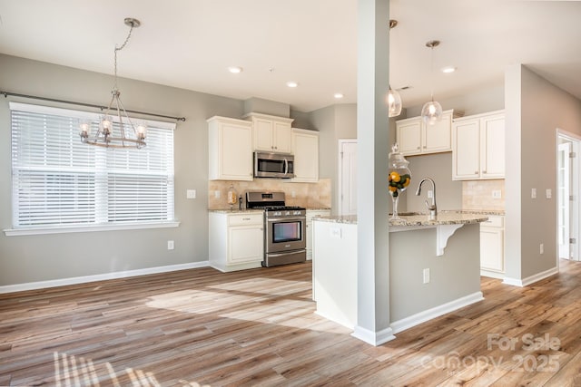 kitchen with white cabinetry, appliances with stainless steel finishes, tasteful backsplash, light stone countertops, and pendant lighting