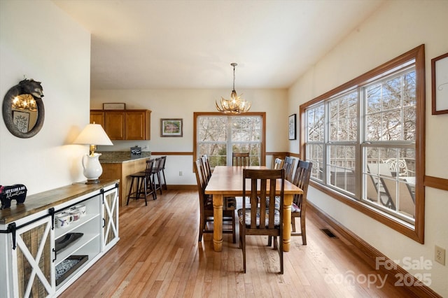 dining room with a notable chandelier and light wood-type flooring